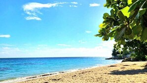 A beach with clear blue water and a sandy shore.