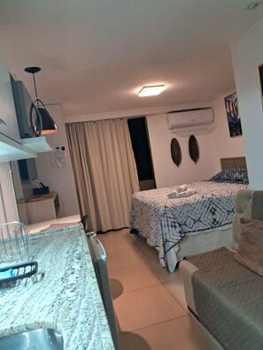 A hotel room with a bed, a desk, a chair, a sink, and an air conditioning unit. - Nomar IX (João Pessoa)