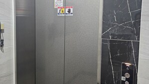 Ein Aufzug mit metallischer Oberfläche, einem digitalen Display und einem Stockanzeiger.