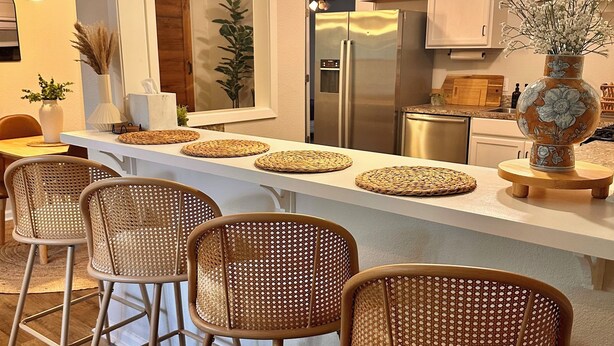 Een moderne keuken met een centraal eiland, barkrukken en een grote spiegel.