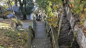 A wooden staircase leading up to a stone wall, surrounded by trees and foliage. - Happy Hideaway in our charming cabin in historic Eureka Springs with jacuzzi tub (Eureka Springs)
