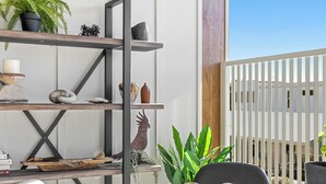 A modern outdoor seating area with a round table, chairs, and a metal shelf unit displaying various decorative items. - Fiano Townhouse 2 Bedrooms (Sunshine Coast)
