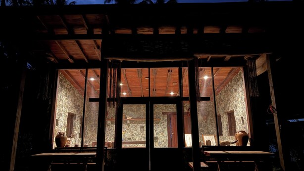 A rustic building with a stone exterior and wooden interior, featuring large windows and a covered outdoor seating area. - Kiao Beach (Puerto Princesa)
