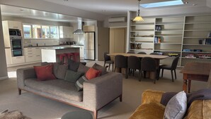 A modern living room with a sofa, a coffee table, and a dining area with a table and chairs. - Alpine Rose Retreat (Arrowtown)