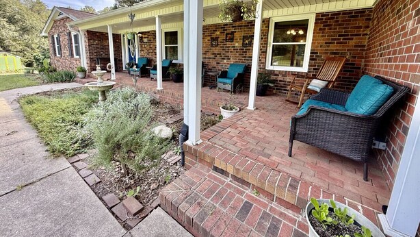 Un patio couvert avec des sièges d’extérieur, des murs en briques et un petit jardin.