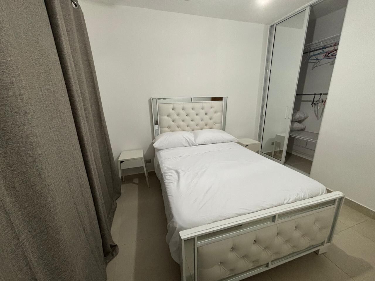 Un dormitorio con cama, mesita de noche, armario y espejo.