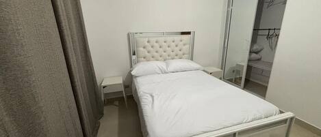 Une chambre à coucher comprenant un lit, une table de chevet, une armoire et un miroir.