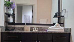 Un baño con tocador negro, un espejo grande y una alfombra roja.