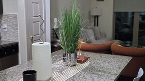 Una cocina con encimera de granito, una puerta blanca y una zona de comedor con mesa y sillas.