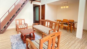 A spacious living area with a wooden staircase, a dining set, and a sofa. - Bedugul Lake View Inn (Baturiti)