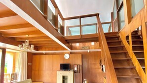 A spacious living area with wooden floors, a staircase, and a chandelier. - Bedugul Lake View Inn (Baturiti)