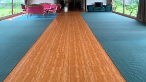 A spacious room with a wooden ceiling, large windows, and a central area with a long wooden floor. - Bedugul Lake View Inn (Baturiti)