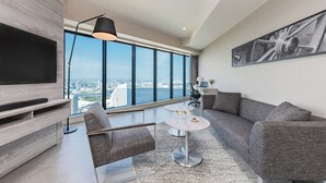 A modern living room with a large TV, comfortable seating, a small round table, and a city view. - OMO5 Yokohama Bashamichi by Hoshino Resorts (Yokohama)