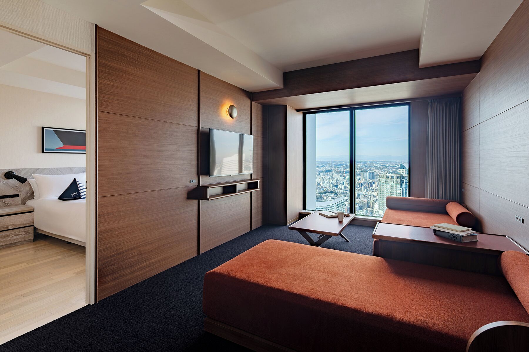 A modern hotel room with a large bed, a desk, a sofa, and a TV.
