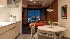 A modern hotel room with a kitchen, dining area, and a large window offering a city view. - OMO5 Yokohama Bashamichi by Hoshino Resorts (Yokohama)