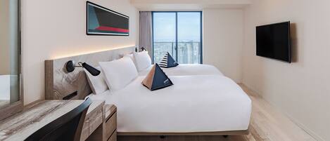 A hotel room with a large bed, a desk, a flat-screen TV, and a city view.