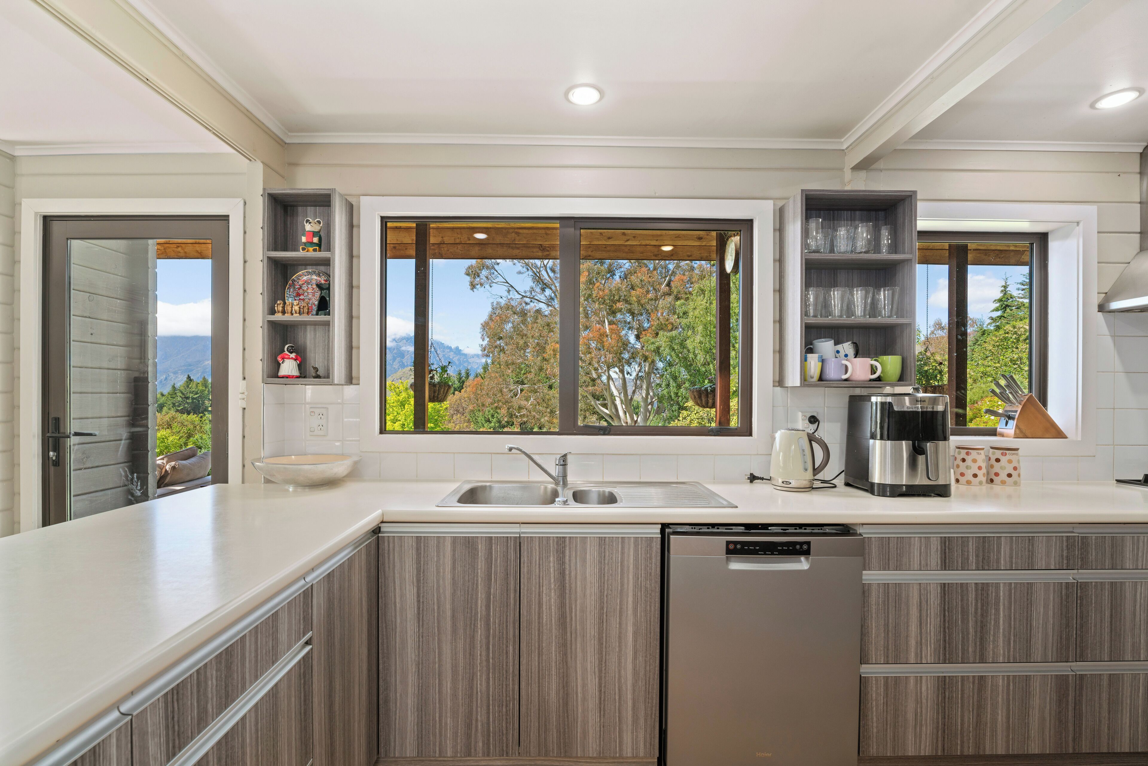 A modern kitchen with a built-in dishwasher, a double sink, and wooden cabinets.