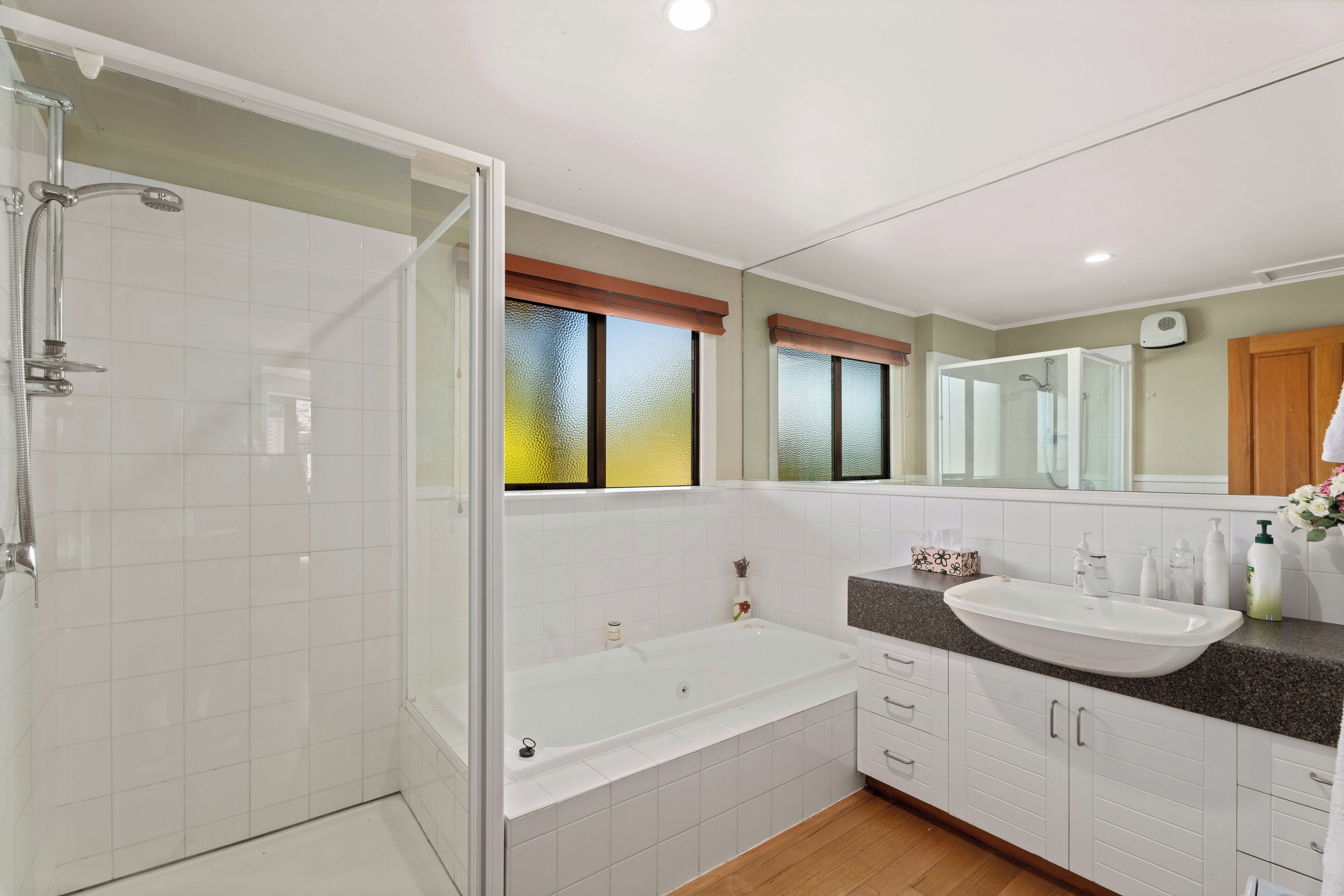 A modern bathroom with a glass-enclosed shower, a freestanding bathtub, a vanity with a sink, and a large mirror.