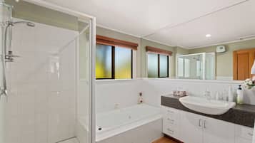 A modern bathroom with a glass-enclosed shower, a freestanding bathtub, a vanity with a sink, and a large mirror.