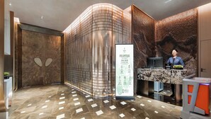 A modern hotel lobby with a reception desk, a large information board, and a patterned wall. - KUNSHANKAICHENJIUDIAN (Suzhou)