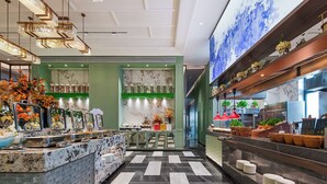 A modern hotel lobby with a marble reception desk, a check-in counter, and a buffet area with various food options. - KUNSHANKAICHENJIUDIAN (Suzhou)