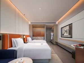 A modern hotel room with two beds, a TV, and a bathroom visible through an open door.