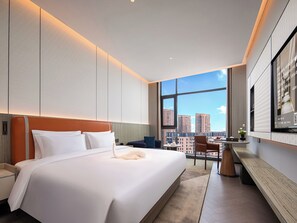 A modern hotel room with a large bed, a desk, and a view of the cityscape. - KUNSHANKAICHENJIUDIAN (Suzhou)