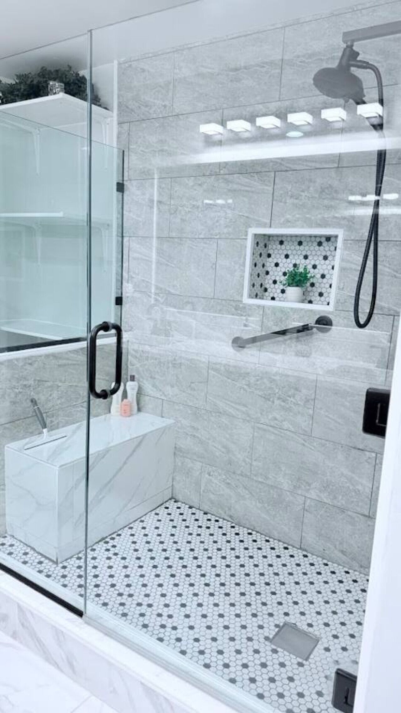 A modern bathroom with a glass shower enclosure, a white sink, and a tiled floor.