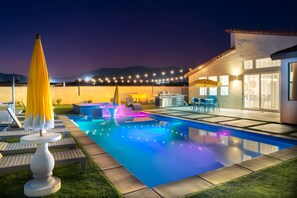 Un espace piscine extérieur moderne doté d’une terrasse, de chaises longues et d’un bar.