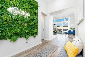 A modern interior with a vertical garden wall, a wooden floor, and a seating area with a patterned rug and cushions. - Pickleball, Gameroom, Pool & Hot Tub, Firepit, BBQ (Desert Hot Springs)