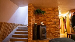A staircase leading to a room with a stone wall and a wood-burning stove.