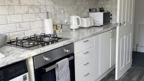 A modern kitchen with white cabinets, a gas stove, a coffee maker, and a microwave.