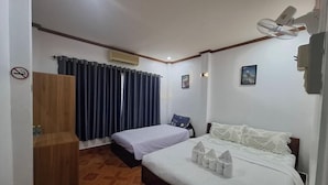 Ein Hotelzimmer mit Bett, Schreibtisch, Stuhl, Kleiderschrank und einem Fenster mit Vorhängen.