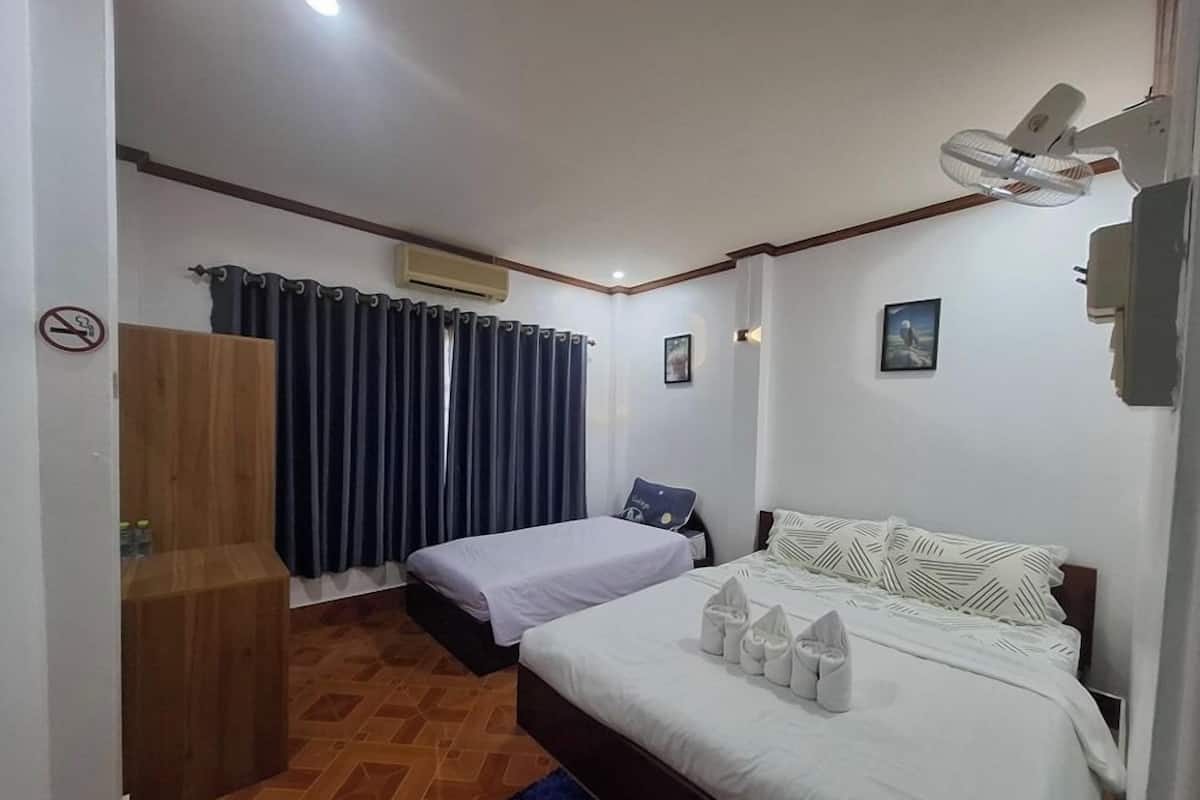 A hotel room with a bed, a desk, a chair, a wardrobe, and a window with curtains.
