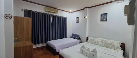 A hotel room with a bed, a desk, a chair, a wardrobe, and a window with curtains.