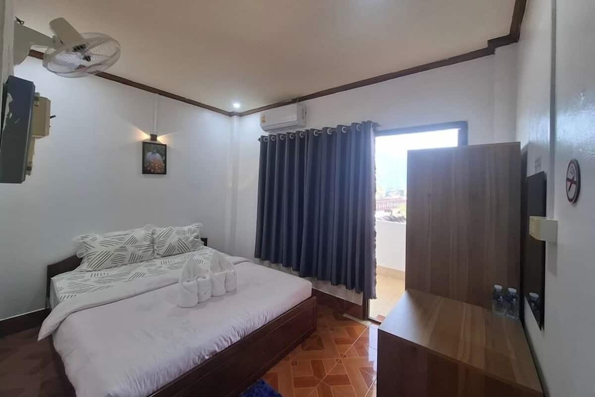 A bedroom with a bed, a ceiling fan, a window with curtains, and a door.