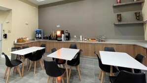 A modern kitchen with a bar area, equipped with a coffee machine, microwave, and various kitchen appliances. - Palace Inn Post Oak (Houston)