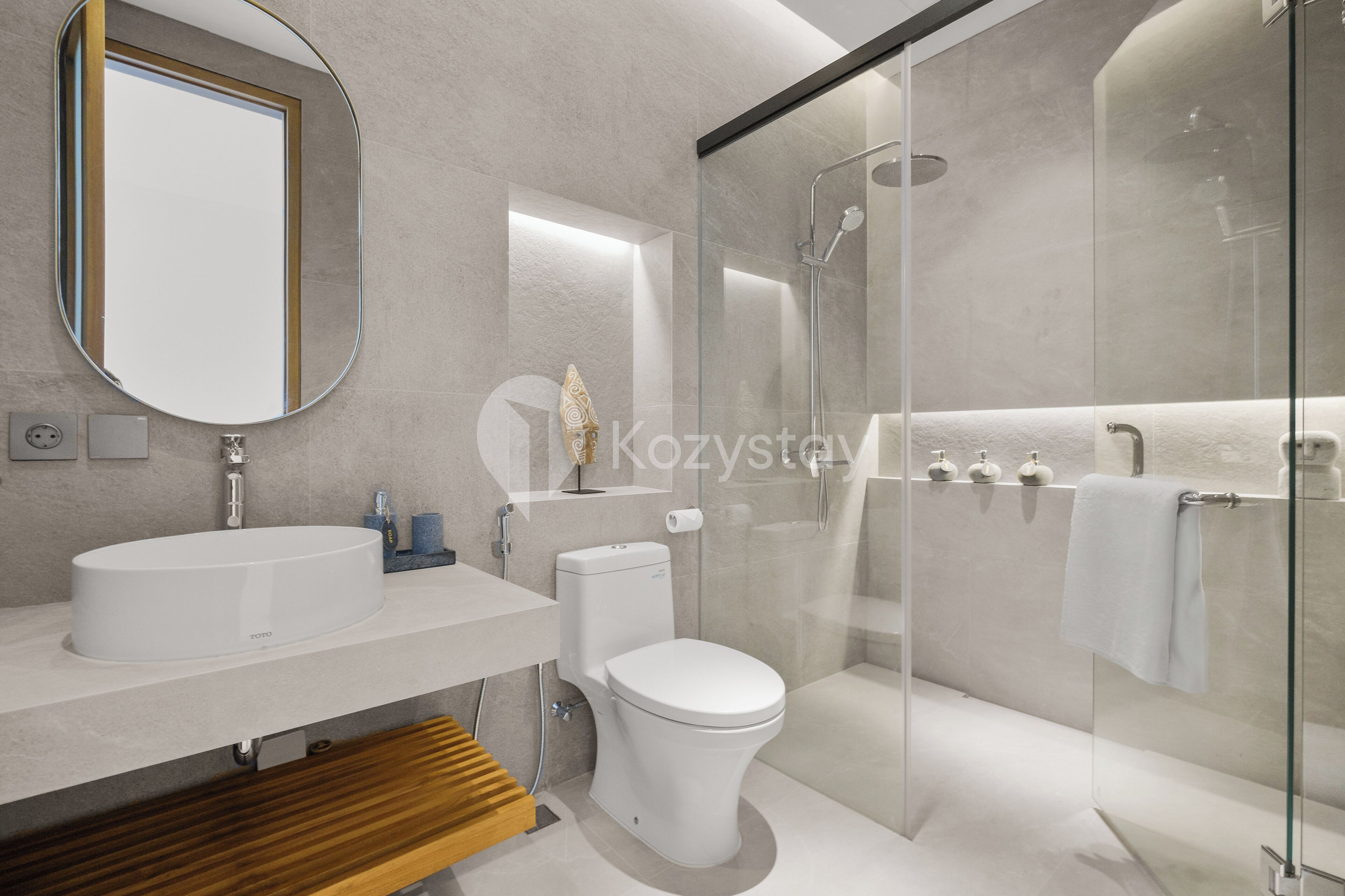 Un baño moderno con ducha de vidrio, lavamanos blanco y un inodoro.