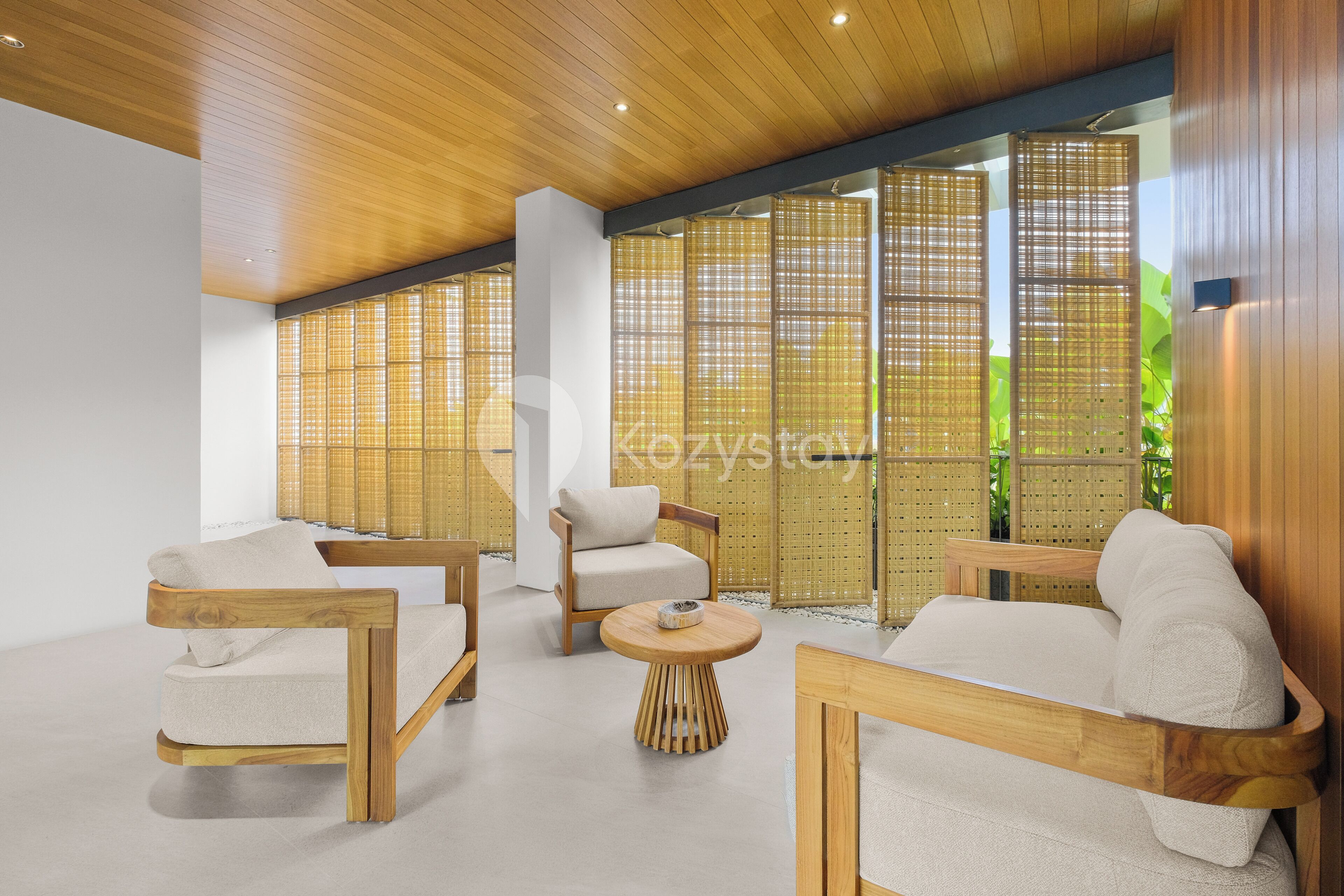Un interior moderno con muebles de madera, una mesa redonda de madera y un ventanal con vistas a zonas verdes.
