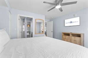 Un dormitorio con cama, ventilador de techo, armario y espejo.