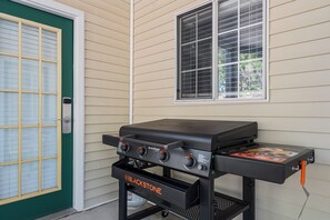 A blackstone grill with four burners, a gas tank, and a side table with a menu. - Polished Condo with Lake Access, Community Outdoor Pool, Mini Golf & Free Attraction Tickets (Kimberling City)