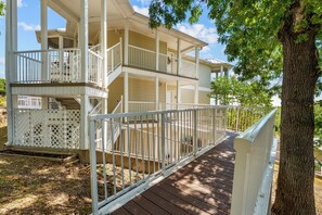 A two-story building with a covered porch and a wooden deck. - Polished Condo with Lake Access, Community Outdoor Pool, Mini Golf & Free Attraction Tickets (Kimberling City)