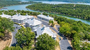 A resort with multiple buildings, a parking lot, and a lake view. - Polished Condo with Lake Access, Community Outdoor Pool, Mini Golf & Free Attraction Tickets (Kimberling City)