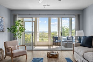 Una sala de estar moderna con un sofá, una silla, una mesa de comedor y vistas a un balcón con barandilla.