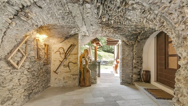 A stone-walled corridor with a wooden door and a view of the outdoors. - Relax In Pineta Beaulard, Oulx, Italy (Oulx)