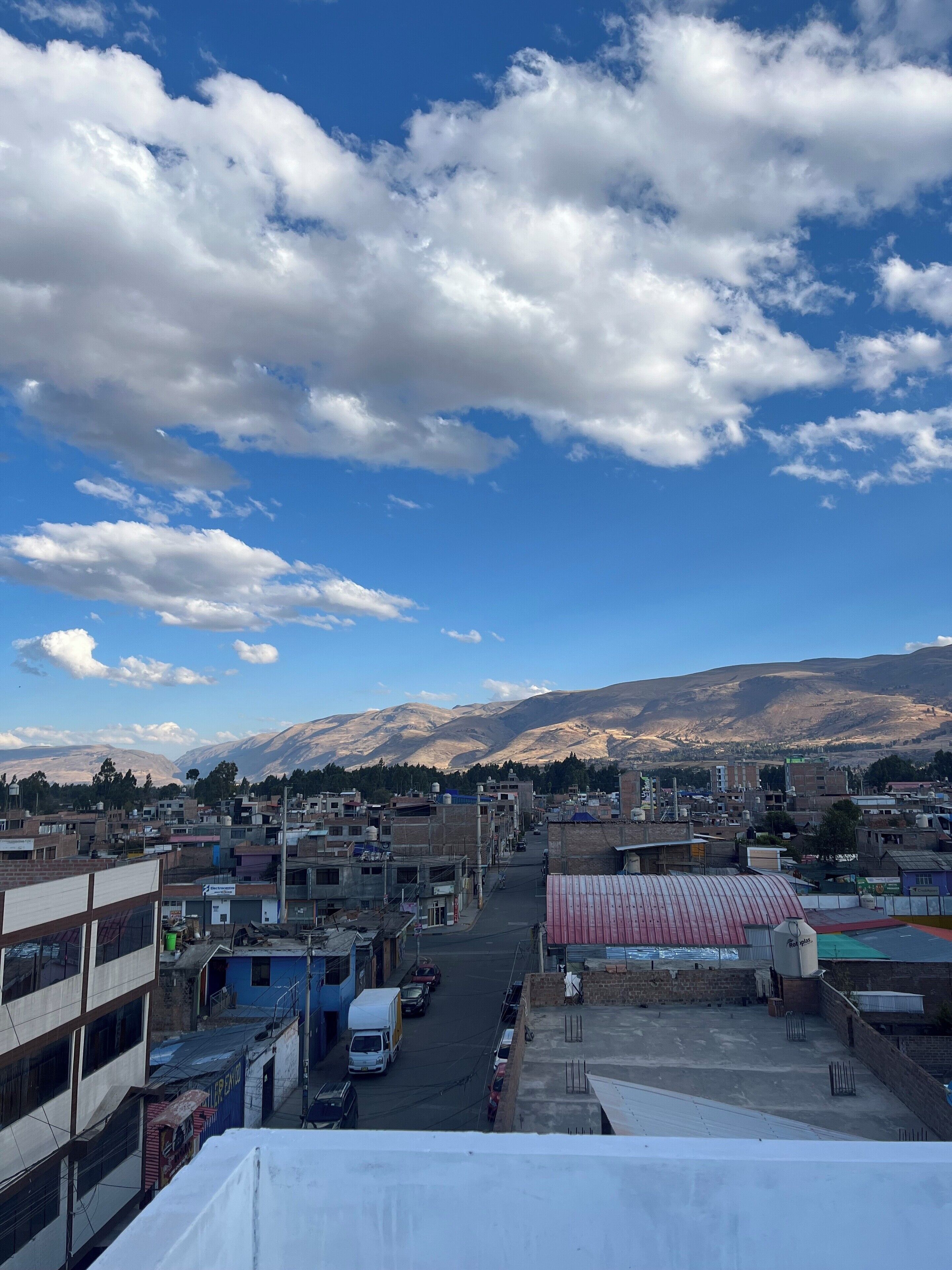 Un paisaje urbano con edificios, una calle y montañas al fondo.