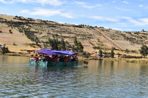 Un grupo de personas en un bote sobre un lago tranquilo con un paisaje montañoso al fondo.