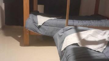 Una cama litera con dos niveles, estructura de madera y ropa de cama gris.