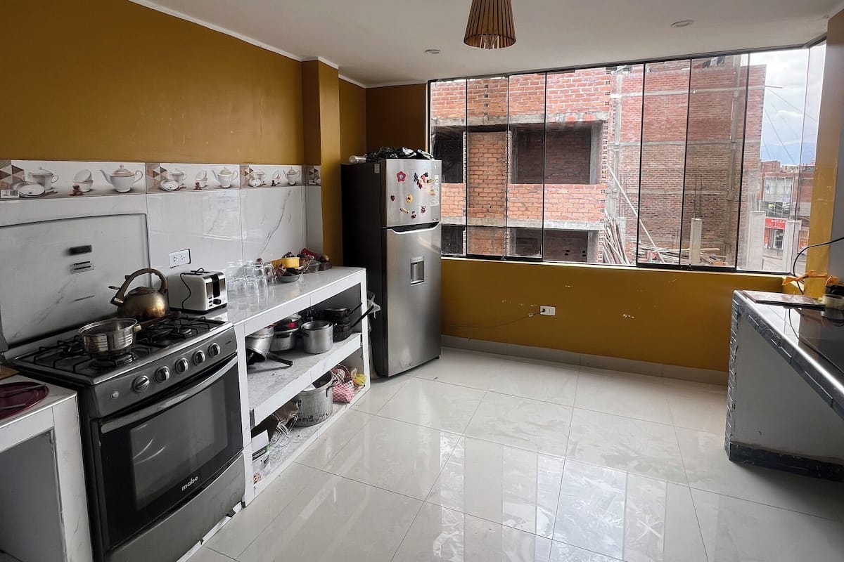 A kitchen with a gas stove, oven, refrigerator, and a window with a view of a brick building.