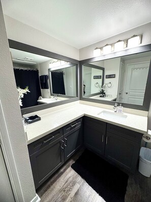 A modern bathroom with two sinks, dark cabinets, and a large mirror. - Modern Executive Suite- NRG, Medical Center, Downtown Houston (Houston)